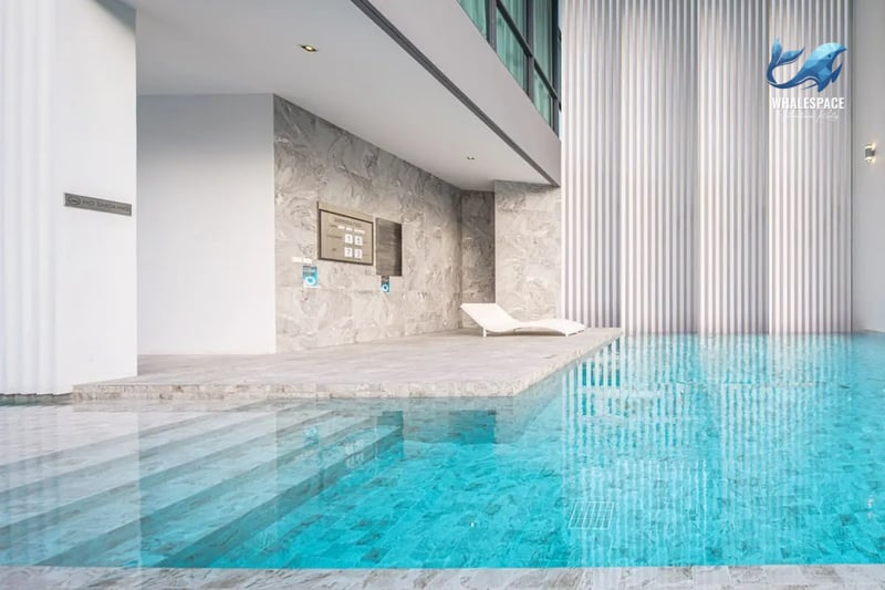 Indoor swimming pool with modern grey stone accents and a sun lounger on the deck