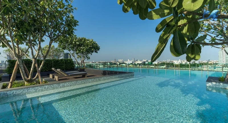 Serene swimming pool with lounge chairs, set against a backdrop of the city skyline.