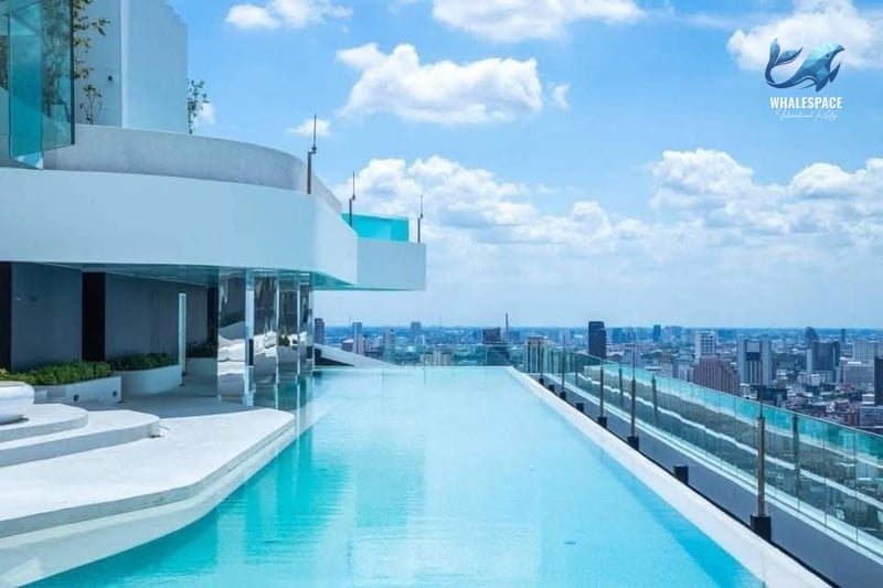 Stunning rooftop infinity pool with white lounge areas and panoramic city views under a clear sky