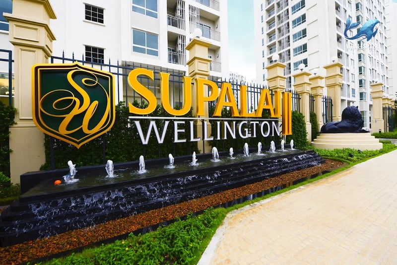 Grand project entrance featuring a large branded sign, decorative lion statue, and water features