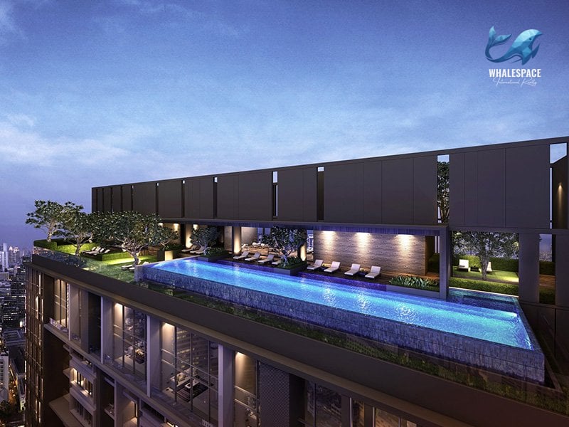 Rooftop infinity pool and lounge area with panoramic city skyline at dusk.