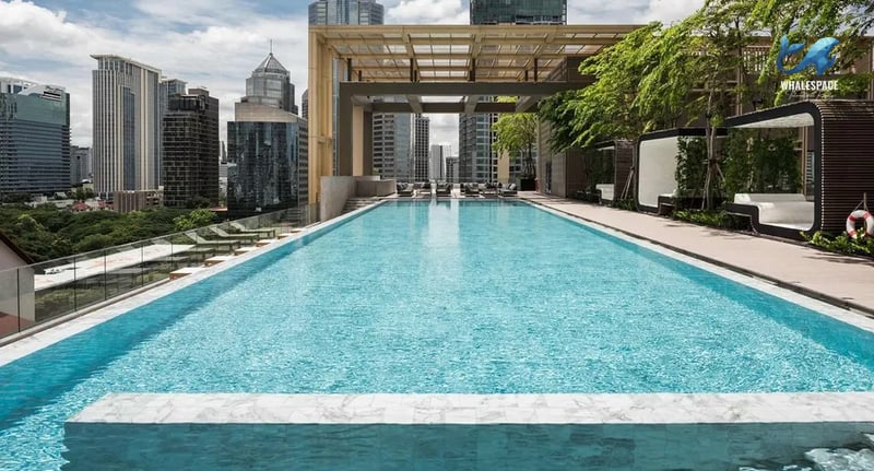 Expansive swimming pool on a rooftop terrace with lush greenery and urban skyline.