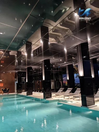 Indoor swimming pool with lounge chairs and a reflective ceiling
