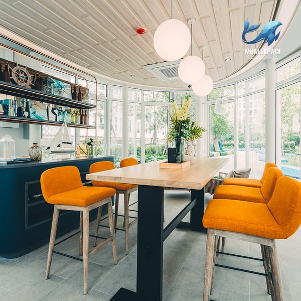 Stylish lounge area with a communal dining table, bar stools, and decorative nautical elements.