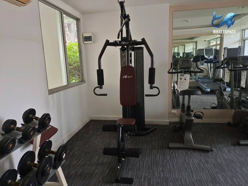 A corner of the gym showcasing a multi-station weight machine and dumbbells.
