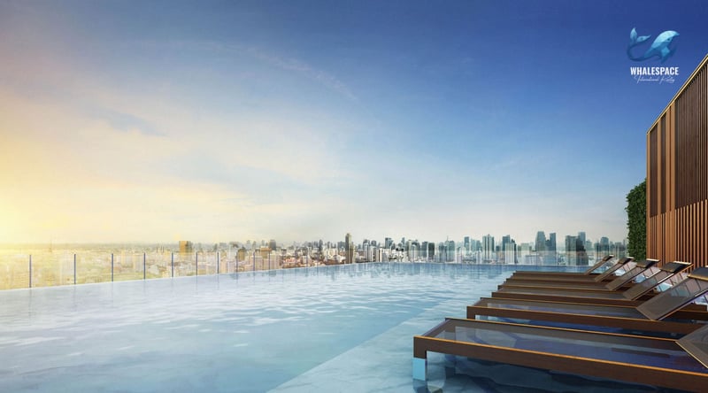 Infinity swimming pool with lounge chairs overlooking a city skyline at sunset