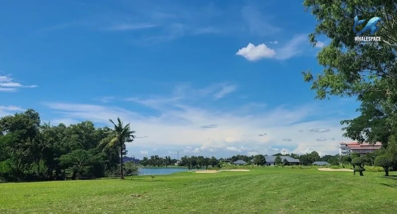 Scenic view of a green golf course under a bright blue sky with scattered clouds.