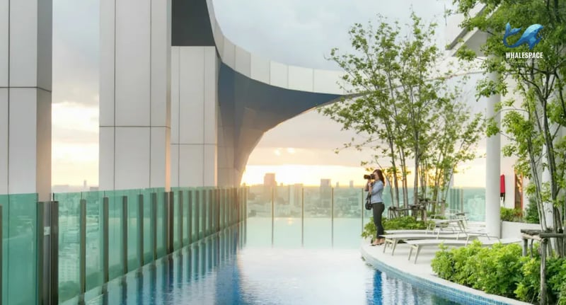 Stunning infinity pool with panoramic city views at sunset, featuring lounge chairs and lush greenery.