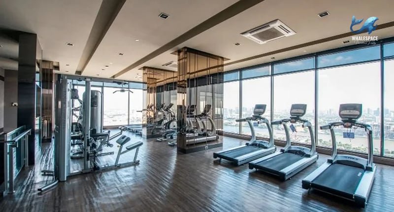 Well-equipped fitness center with treadmills, elliptical machines, and weight training equipment, overlooking the city skyline.