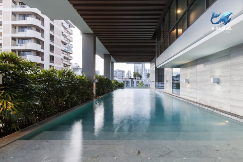 Lap pool with city views and lush greenery, featuring modern architecture and marble flooring.