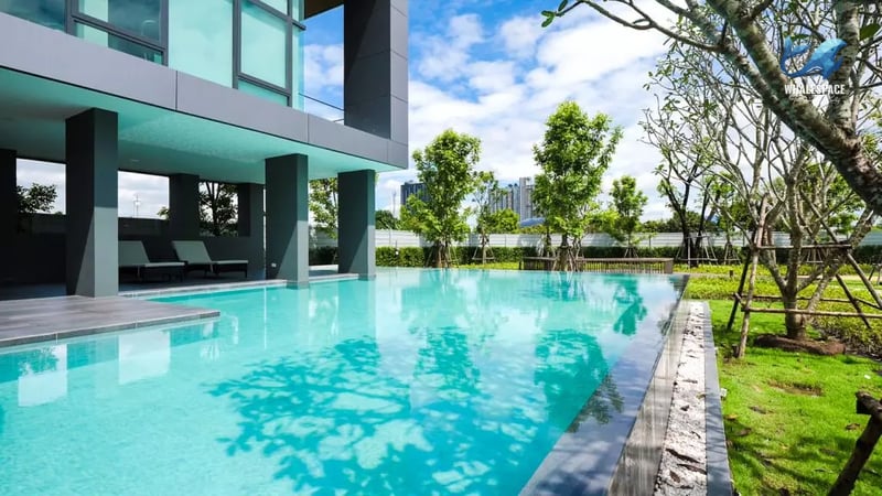 Inviting lap pool with sleek dark grey pillars and lush green landscaping