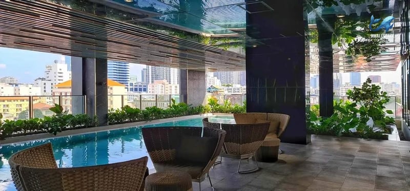 Serene swimming pool area with comfortable seating and lush greenery overlooking the city skyline.
