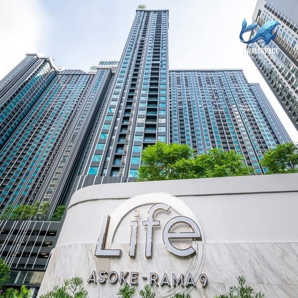 Modern high-rise condominium buildings with sleek glass facades and lush green landscaping at the entrance