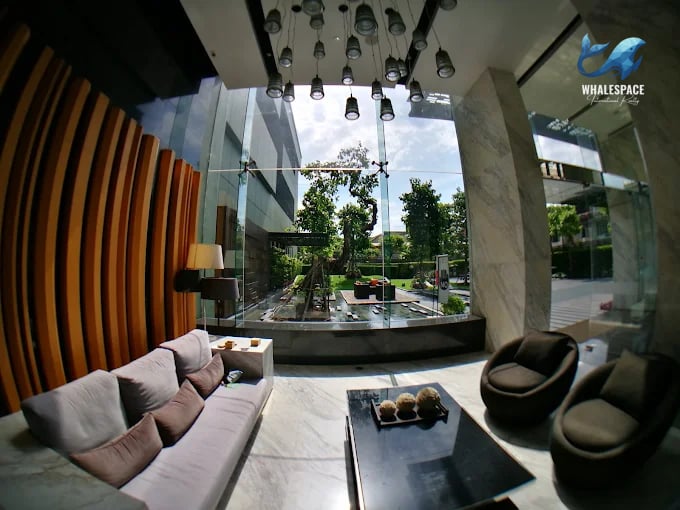 Elegant lobby with plush seating, marble flooring, and a striking contemporary light fixture, overlooking a tranquil garden space.