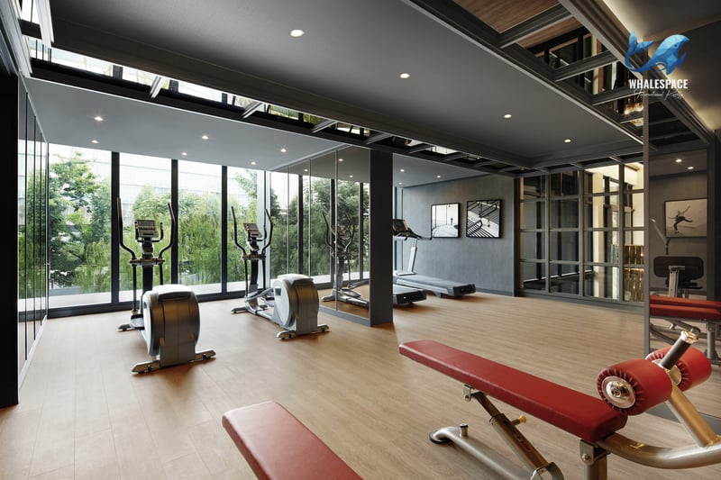 Modern fitness center with a range of exercise equipment, large floor-to-ceiling windows, and a warm wooden floor.