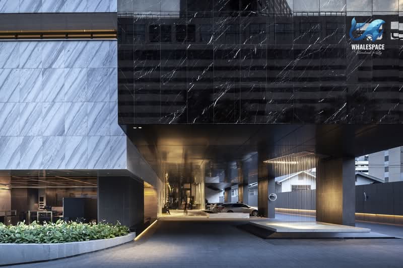 Grand entrance of a contemporary building featuring a sophisticated design with marble accents and a landscaped driveway