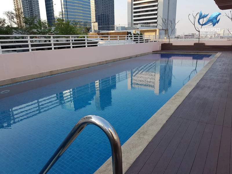 Outdoor swimming pool with city skyline reflections on the water, surrounded by a composite wood deck.