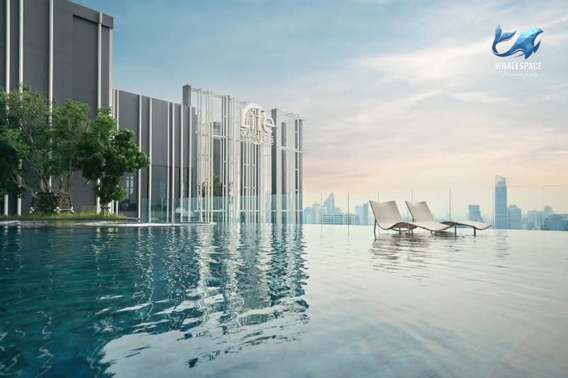 Infinity pool on a rooftop with comfortable lounge chairs and a panoramic city skyline view.
