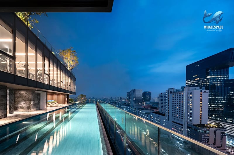 Infinity pool at dusk with city skyline views and gym facilities above.