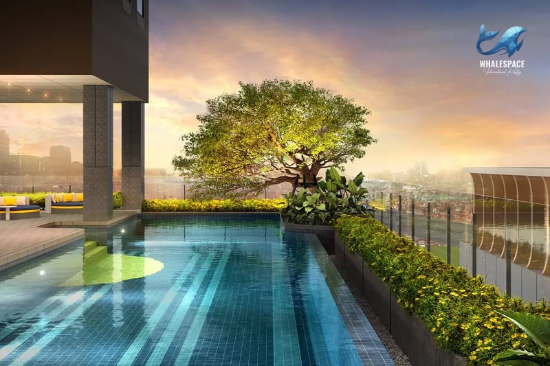 Rooftop infinity pool overlooking a cityscape at sunset, with lush greenery and lounge seating.