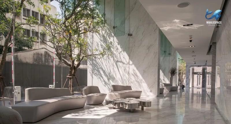 Expansive marble lobby with contemporary curved sofas and artistic metallic coffee tables, bathed in natural light.