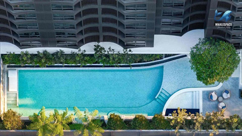 Aerial view of a serene swimming pool surrounded by lush greenery and modern architecture.