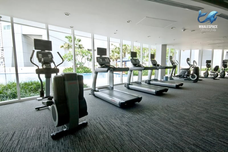 Well-equipped fitness center with treadmills and cardio machines overlooking the pool.