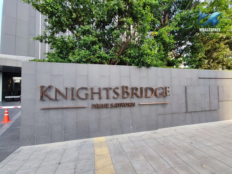 Modern building facade with prominent 'KNIGHTSBRIDGE PRIME SATHORN' signage and lush greenery.
