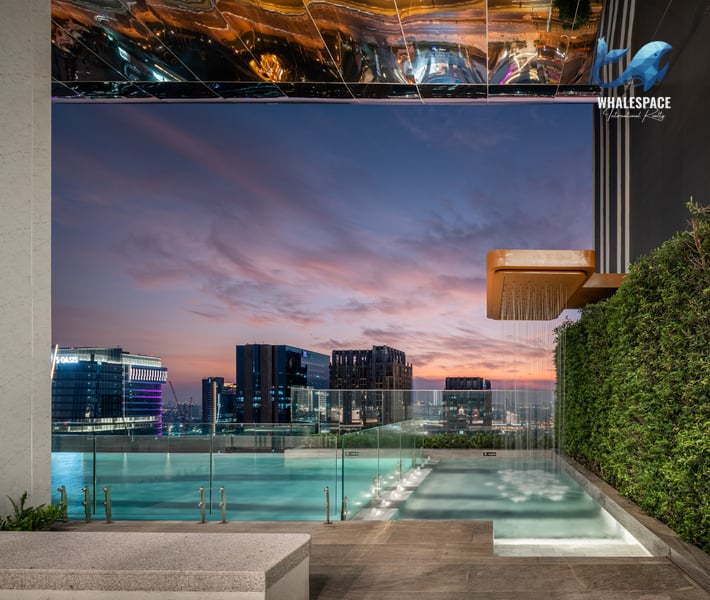 Rooftop infinity pool with stunning city views at sunset, featuring a modern outdoor shower.