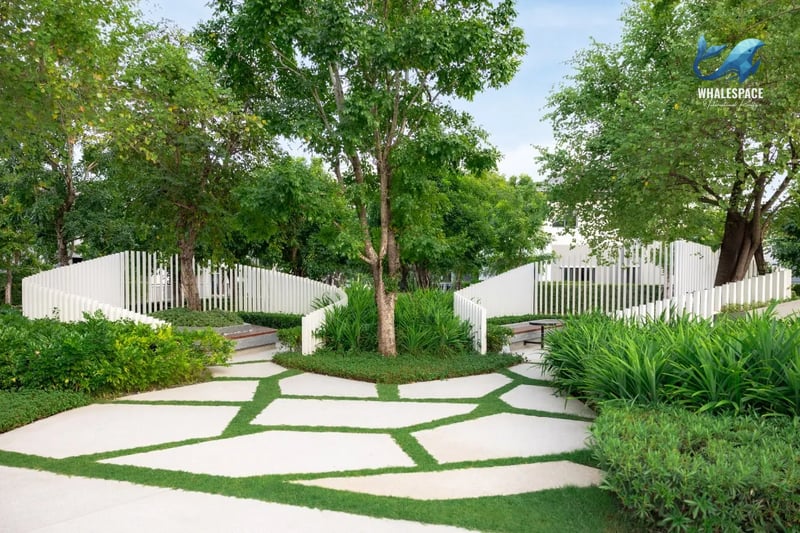 Lush green garden pathway with abstract white fencing and ample shaded seating areas