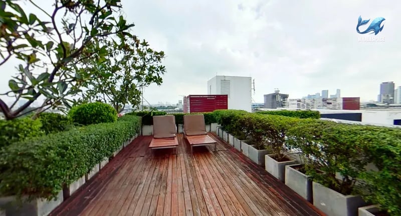 Relaxing rooftop area featuring wooden decking with two chaise lounges, offering serene city views.