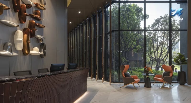 Elegant reception area with a sleek marble counter, abstract art on the wall, and plush armchairs near floor-to-ceiling windows.