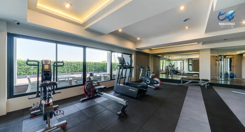 State-of-the-art fitness center with various cardio machines and weight training equipment, featuring large windows with green views.