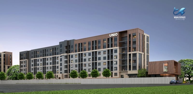 Modern condominium building with multi-toned facade, featuring wood accents and subtle lighting, surrounded by green landscaping.