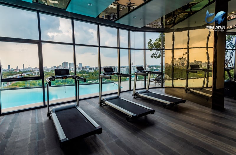 Fitness room with treadmills, large windows, and a view of the city and pool below.