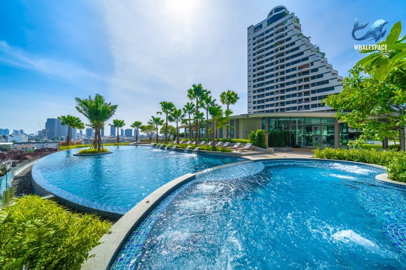Expansive elevated swimming pool area with palm trees, lounge chairs, and city views