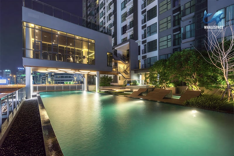 Evening view of a resort-style swimming pool with lounge chairs and ambient lighting.