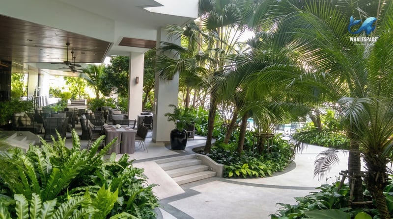 Outdoor dining area adjacent to a beautifully landscaped garden with palm trees