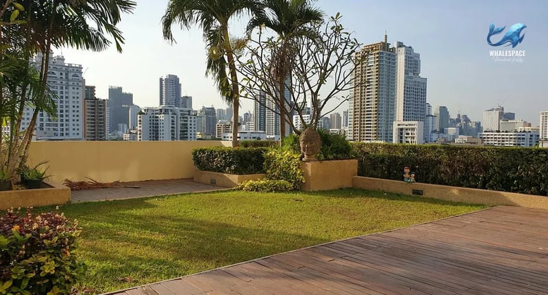Expansive rooftop deck with a manicured lawn, wooden flooring, and panoramic city skyline views, ideal for relaxation and entertaining.