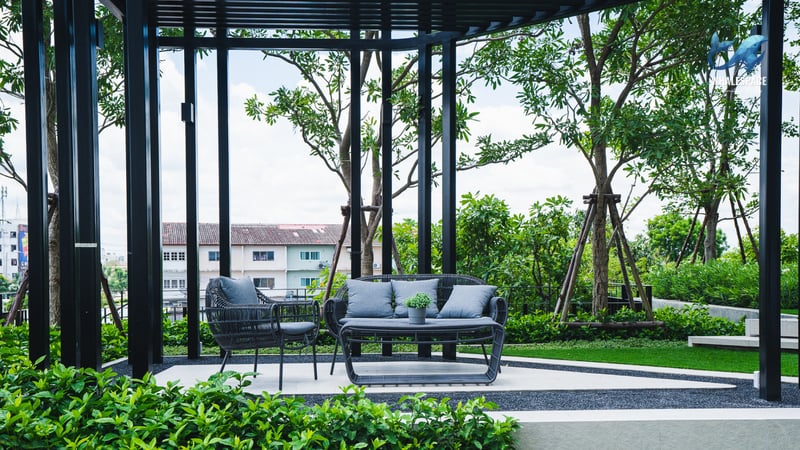 Outdoor lounge area with contemporary wicker seating amidst green landscaping