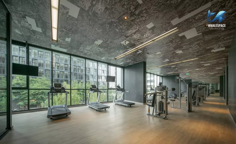 Well-equipped fitness center with treadmills, weight machines, and large windows offering city views.