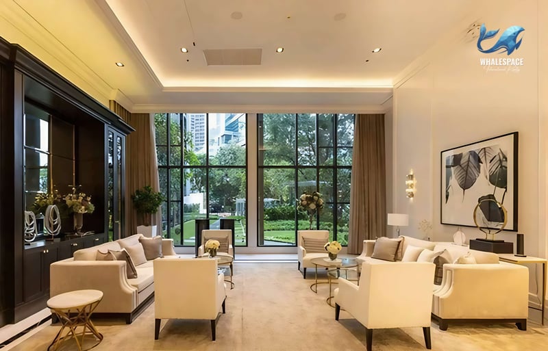 Sophisticated residents' lounge featuring plush cream sofas, elegant decor, and large windows overlooking a lush garden.