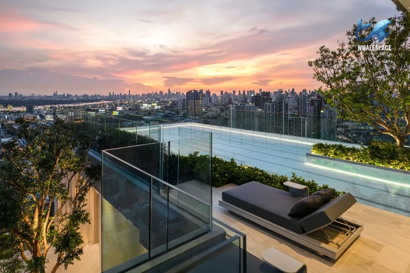 Luxury rooftop infinity pool reflecting a vibrant sunset, with comfortable lounge seating and expansive city views.