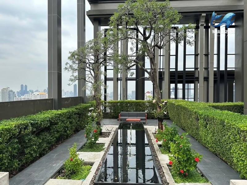 Lush rooftop garden featuring a long, narrow water feature, manicured hedges, and a modern outdoor sofa.