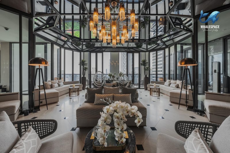 Opulent lounge with a dramatic chandelier, elegant seating arrangements, and expansive city views through a glass ceiling.
