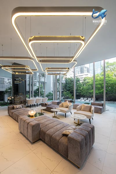 Elegant lounge area with plush seating, contemporary lighting, and large windows offering garden and pool vistas.