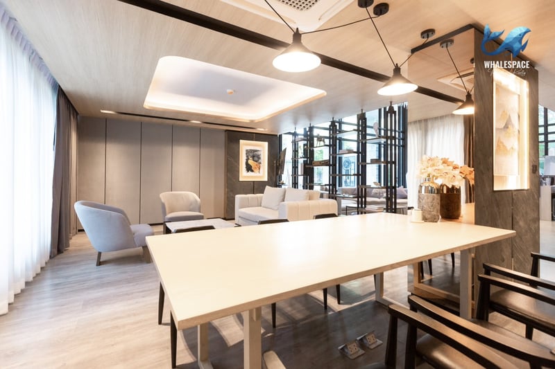 Stylish communal lounge featuring a long shared table, comfortable seating areas, and modern artwork under recessed lighting.
