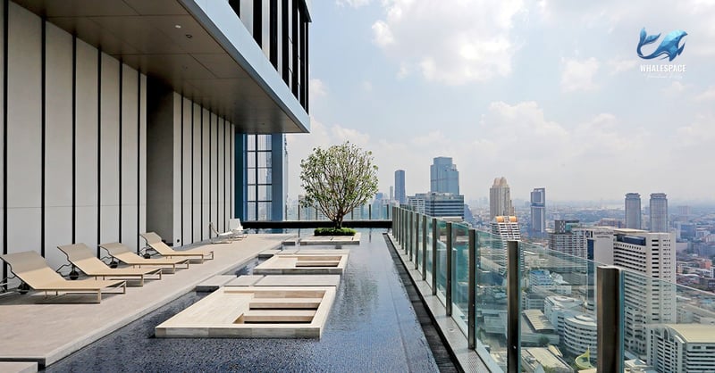 Elevated outdoor swimming pool featuring submerged lounge platforms and sun loungers, set against a backdrop of expansive city views