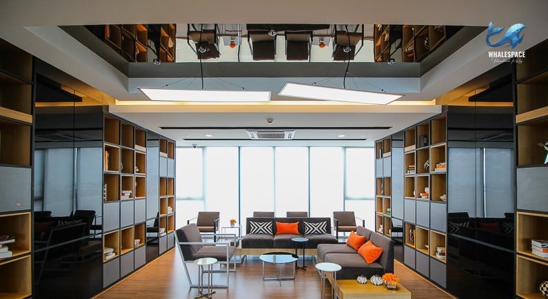 Elegant lounge area with comfortable seating, bookshelves, and a mirrored ceiling.