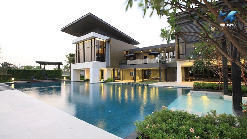 Expansive swimming pool with clear blue water, adjacent to a contemporary house with an angled roofline.